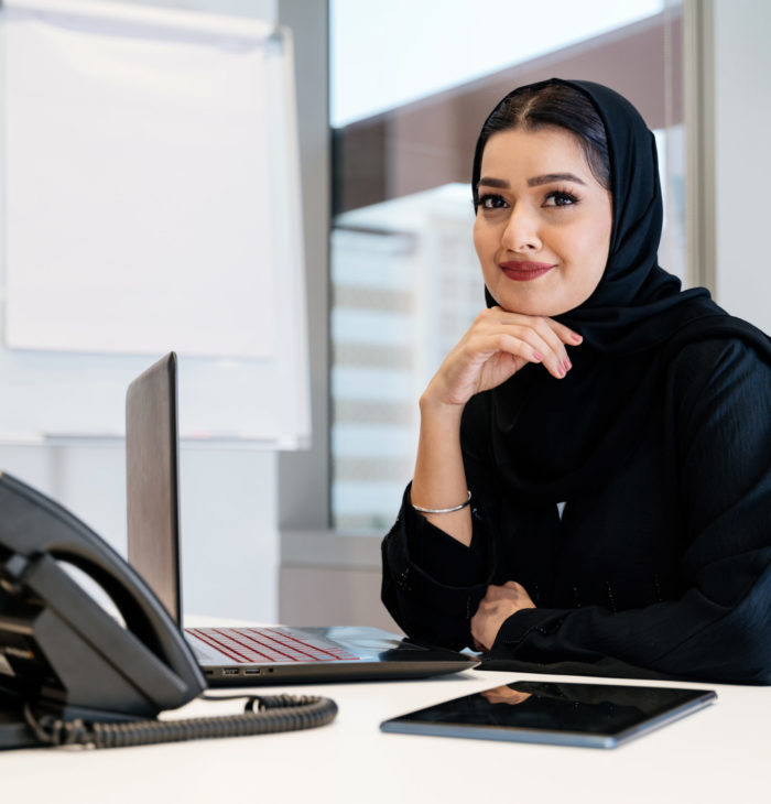 Portrait of beautiful middle-eastern corporate businesswoman wearing abaya and working in the office in Dubai